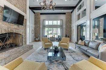 A living room with a stone fireplace and yellow chairs.